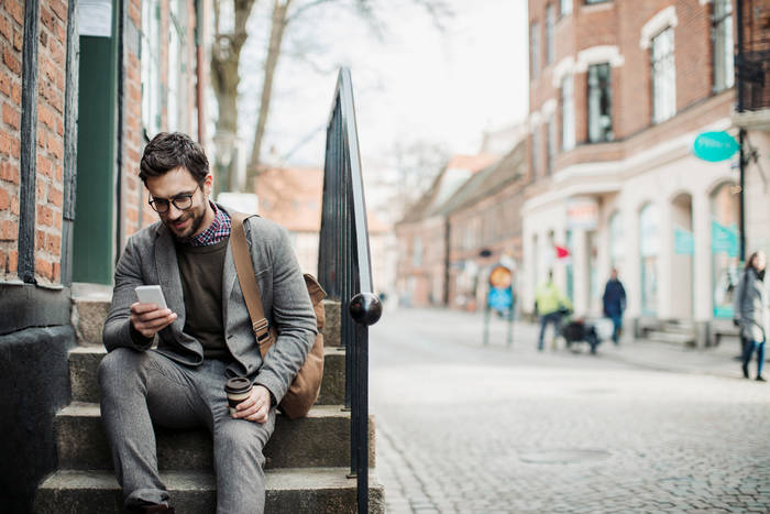 man sitting on stairs with smart phone